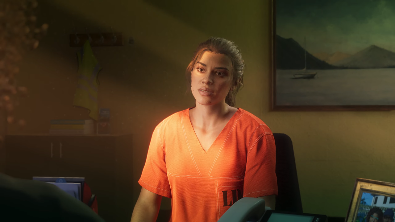 GTA 6 screenshot of Lucia sitting in the prison office wearing orange prison clothes looking on.