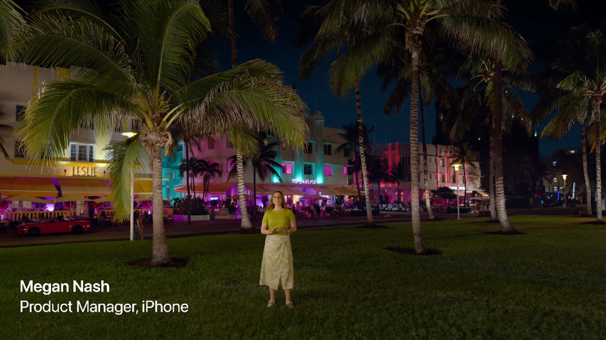 a product manager for apple stands on the grass in front of a lighted up building in miami at night